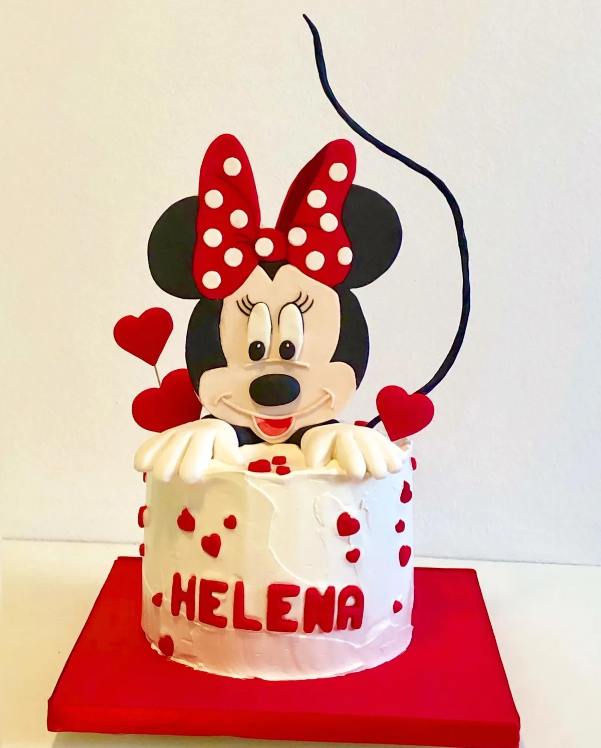 Bolo 1 andar da Minnie com figura 3D saindo do topo, braços apoiados na borda e corações vermelhos com nome HELENA