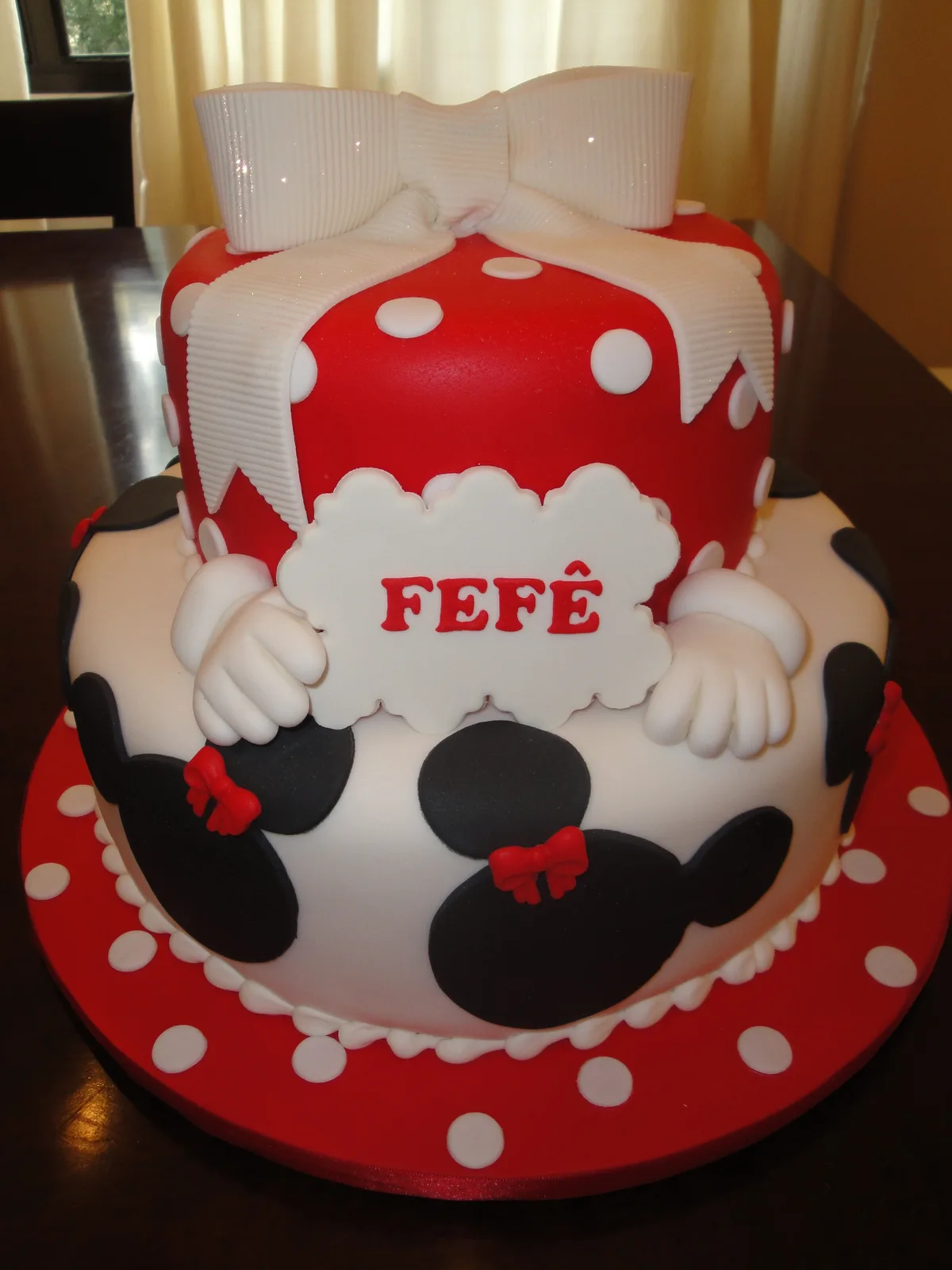 Bolo 2 andares da Minnie personalizado com nome FEFÊ em vermelho com bolinhas brancas e laço